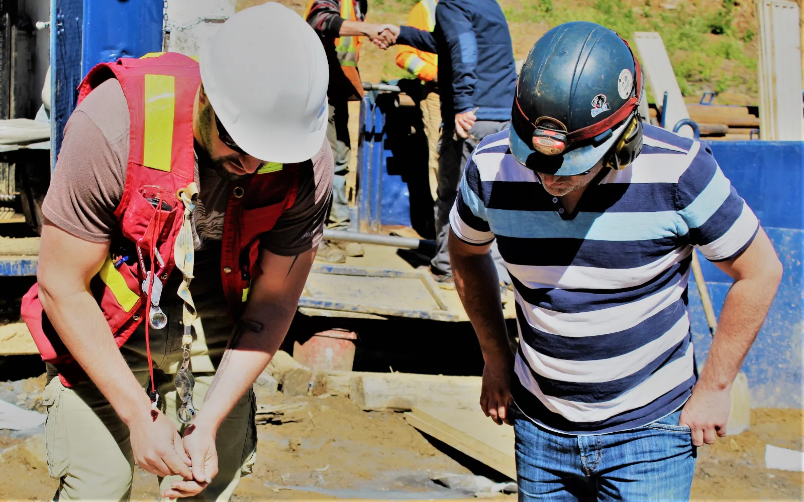 Mining professionals looking at a sample with hardhats.