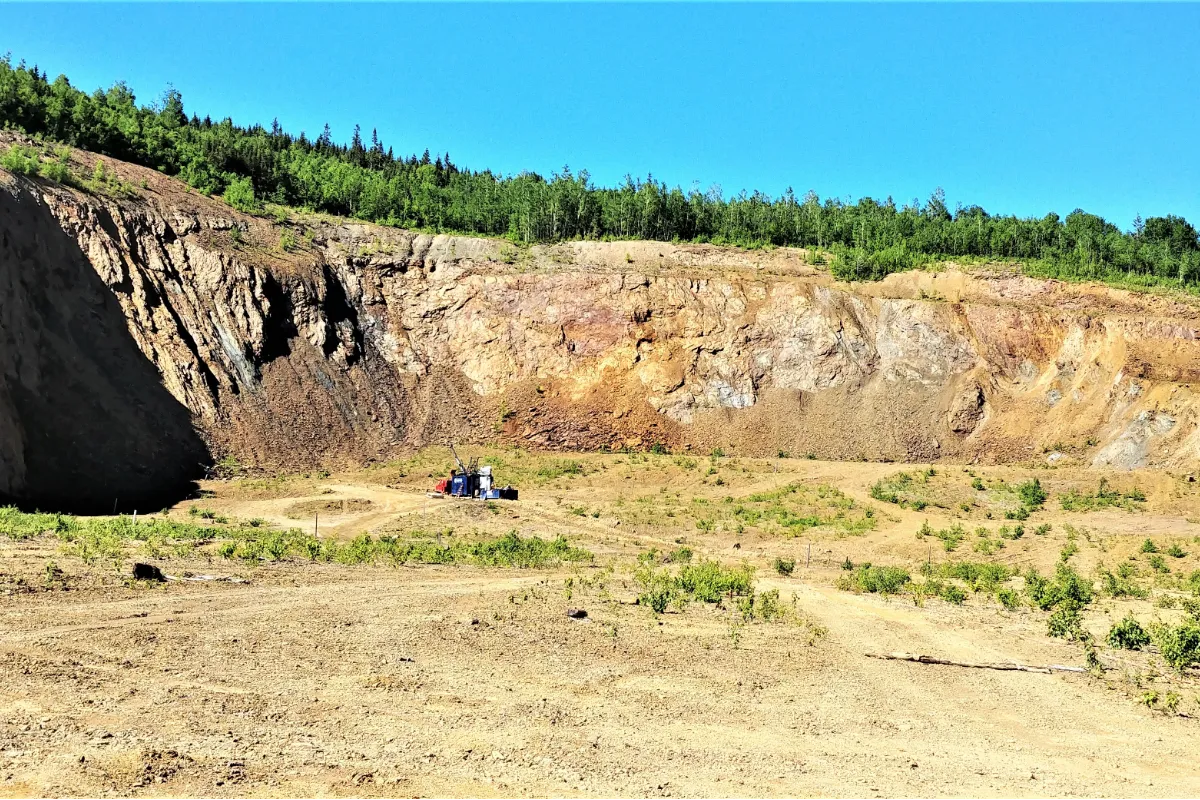 Open mine, hillside with forest at top.
